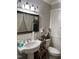 Well-lit bathroom with a classic sink, mirror, and organized toilet storage at 405 Taylor Dr, Rocky Mount, NC 27803
