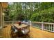 View of the wooden deck featuring built-in seating, dining area, and outdoor grill with mature trees in background at 406 Bakewell Ct, Wake Forest, NC 27587