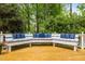 View of the wooden deck featuring built-in seating with blue pillows amongst mature trees and landscaping at 406 Bakewell Ct, Wake Forest, NC 27587
