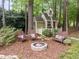 Charming backyard features a fire pit with Adirondack chairs and a whimsical playhouse in a wooded setting at 406 Bakewell Ct, Wake Forest, NC 27587