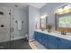 Stylish bathroom featuring a double vanity with blue cabinets, a walk-in shower, and modern fixtures at 406 Bakewell Ct, Wake Forest, NC 27587