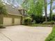Home exterior with two-car garage, spacious driveway, mature trees, and landscaping at 406 Bakewell Ct, Wake Forest, NC 27587