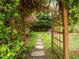 View of stone path through a lush garden featuring an archway covered in vines leading to the backyard at 406 Bakewell Ct, Wake Forest, NC 27587