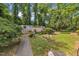 Tranquil backyard with a serene garden, mature trees, and a walkway leading to a storage shed or guest house at 424 Raleigh View Rd, Raleigh, NC 27610