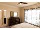 Bright bedroom featuring neutral walls, a ceiling fan, large dresser with mirror, and light-filled window with floral curtains at 428 Parlier Dr, Apex, NC 27523