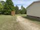Backyard featuring a gravel driveway and a storage shed, with a well-maintained lawn and a tree line at 4855 Mike Ln, Nashville, NC 27856