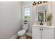 Bright half-bathroom with a single sink vanity and toilet near a sunny window at 5337 Nc Hwy 96, Selma, NC 27576