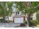 Two-story home boasts mature trees, complementing the white siding and brick accented garage at 5456 Grand Traverse Dr, Raleigh, NC 27604