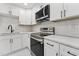 Modern kitchen with new stainless steel appliances and updated white cabinets, countertops, and tiled backsplash at 620 Wexford Dr, Raleigh, NC 27603