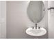 Modern half-bathroom featuring a pedestal sink, oval mirror, and sleek fixtures with white walls at 63 W Victoria Ridge Dr # 31, Selma, NC 27576