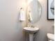 Well-lit powder room with pedestal sink, oval mirror, and neutral paint at 6341 Grace Lily Dr, Raleigh, NC 27607