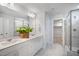 Bright bathroom with double vanity, white marble, and a glass-enclosed shower, plus an adjacent walk-in closet at 680 Beacon Hill Rd # 52, Lillington, NC 27546