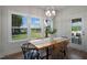 Sunlit dining room featuring a rustic wood table, modern chandelier, and serene backyard views at 680 Beacon Hill Rd # 52, Lillington, NC 27546