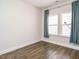 A minimalist bedroom showcasing hardwood floors and two windows adorned with stylish teal curtains, offering ample natural light at 816 Still Willow Ln, Wendell, NC 27591