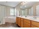 Bright bathroom featuring a double sink vanity, soaking tub with tile surround and a glass enclosed shower at 1007 Grandover Dr, Durham, NC 27713