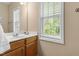 Bright bathroom featuring a white sink, wood cabinets, and a large window at 1007 Grandover Dr, Durham, NC 27713