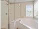 Bright bathroom featuring a large soaking tub with tile surround and a glass enclosed shower at 1007 Grandover Dr, Durham, NC 27713