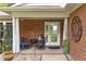 Inviting covered front porch with seating area, decorative accents and brick surround at 102 Fairgrove Way Way, Cary, NC 27511