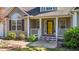 Inviting front porch with white railings and a bright yellow front door, flanked by well-maintained landscaping at 106 Contender Dr, Clayton, NC 27520