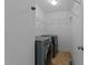 Well-lit laundry room with two washing machines, shelving and neutral colored walls at 106 Contender Dr, Clayton, NC 27520