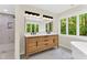 Elegant bathroom with a double vanity, contemporary lighting, and a large mirror reflecting natural light from a window at 106 Silverwood Ln, Cary, NC 27518