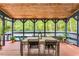 Inviting screened outdoor dining area features wood ceiling and view of backyard pool and lush greenery at 106 Silverwood Ln, Cary, NC 27518