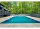 Beautiful in-ground pool surrounded by a concrete deck and a dark gray fence with a wooded backdrop at 106 Silverwood Ln, Cary, NC 27518