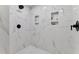 Detail of a marble-tiled shower with built-in niches, a rainfall showerhead, and sleek hardware for a modern look at 106 Silverwood Ln, Cary, NC 27518