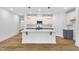 Bright kitchen features white cabinets, an island with bar seating, stainless appliances, and pendant lighting at 109 Imagine Way, Pittsboro, NC 27312