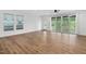 Open-concept living room with wood floors, large windows, ceiling fan, and sliding glass doors to the backyard at 109 Imagine Way, Pittsboro, NC 27312