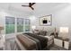 Staged primary bedroom with carpet, ceiling fan, tray ceiling, and three large windows with wooded backyard views at 109 Imagine Way, Pittsboro, NC 27312