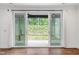View from a living room looking out of sliding glass doors to a patio area with green backyard views at 109 Imagine Way, Pittsboro, NC 27312