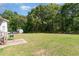 Open backyard showcasing the home, lush trees and an outdoor cooking area at 116 Meade Dr, Four Oaks, NC 27524