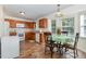 Eat-in kitchen with wood cabinets and white appliances includes table with seating near a large window at 116 Meade Dr, Four Oaks, NC 27524