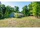 A big backyard, surrounded by many trees, with a view of the back of the home at 116 Shawnee Dr, Louisburg, NC 27549