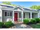 Close up of a charming front porch with red door, surrounded by mature landscaping at 116 Shawnee Dr, Louisburg, NC 27549