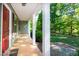 Inviting front porch with white columns, a red door, and a view of the landscaped yard at 116 Shawnee Dr, Louisburg, NC 27549