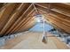 Spacious attic featuring exposed wooden beams, plywood flooring, and insulation at 128 Cobblestone Dr, Chapel Hill, NC 27516