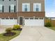 Beautiful townhome exterior with a two-car garage, brick accents, a dark front door, and colorful front yard plants at 138 Boarstall Crk, Durham, NC 27707