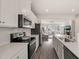 Modern kitchen featuring white cabinets, stainless steel appliances, white countertops, and an open view to the living room at 138 Boarstall Crk, Durham, NC 27707