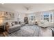 Bright living room with a grey sofa, white armchairs, large windows, and an elegant blue patterned rug at 138 Boarstall Crk, Durham, NC 27707