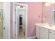 Well-lit bathroom featuring tile flooring, white cabinets, and pink accent wall at 144 Elk Stone Trl, Garner, NC 27529