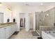 Luxurious bathroom featuring dual sinks, white cabinetry, a glass-enclosed shower, and a soaking tub at 144 Elk Stone Trl, Garner, NC 27529