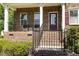 Charming front porch with brick facade, black iron railings, and comfortable seating area with accent door at 144 Elk Stone Trl, Garner, NC 27529