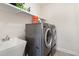 Modern laundry room featuring grey front-loading machines and a utility sink at 144 Elk Stone Trl, Garner, NC 27529
