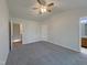 Cozy bedroom featuring neutral walls, a ceiling fan, soft carpeting, and easy access to the ensuite bath at 1610 Oxleymare Dr, Raleigh, NC 27610