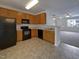Efficient kitchen featuring wood cabinets, black appliances, and seamless flow into the open-concept living area at 1610 Oxleymare Dr, Raleigh, NC 27610