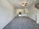 Open concept living room with soft gray carpet, ceiling fan, and abundant natural light from sliding glass doors at 1610 Oxleymare Dr, Raleigh, NC 27610
