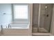 Bathroom featuring soaking tub beneath window and glass-enclosed shower stall with tiled walls and shower seat at 1635 Pecan Drive # 26, Nashville, NC 27856