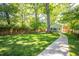 Expansive backyard with lush lawn, mature trees, and a pathway leading to a charming detached garage at 1714 Carson St, Raleigh, NC 27608